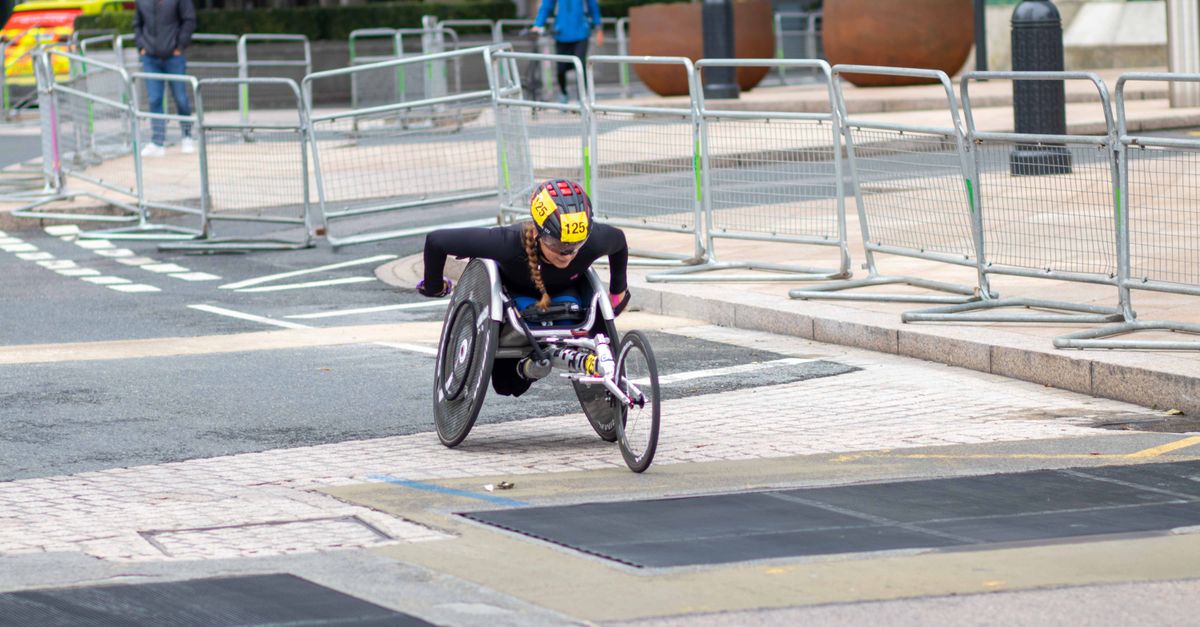 A dedicated athlete competes in a marathon using a racing wheelchair on city streets.