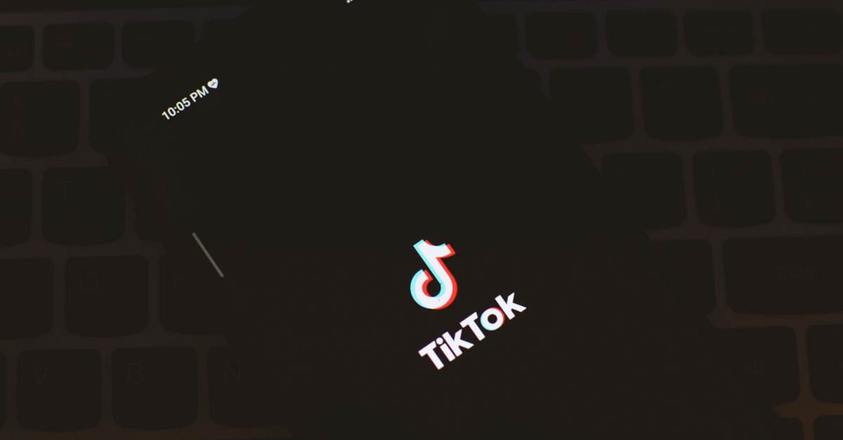 TikTok destrona a Google, Tendencia social media technology: Close-up of a smartphone displaying the TikTok app logo against a dark keyboard background.