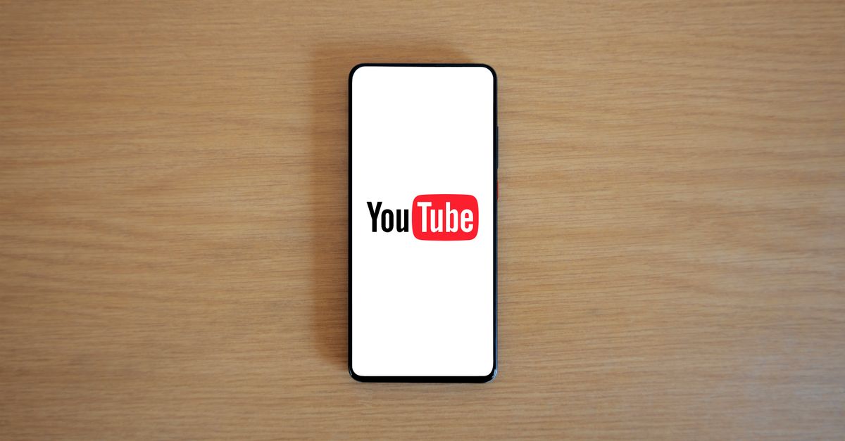 monetizar con videos en YouTube: Top view of smartphone displaying YouTube logo on a wooden surface, showcasing modern technology.