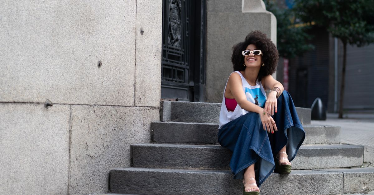 moda sostenible y estilo personal: Young woman in stylish attire sitting on steps in Buenos Aires on a sunny day.