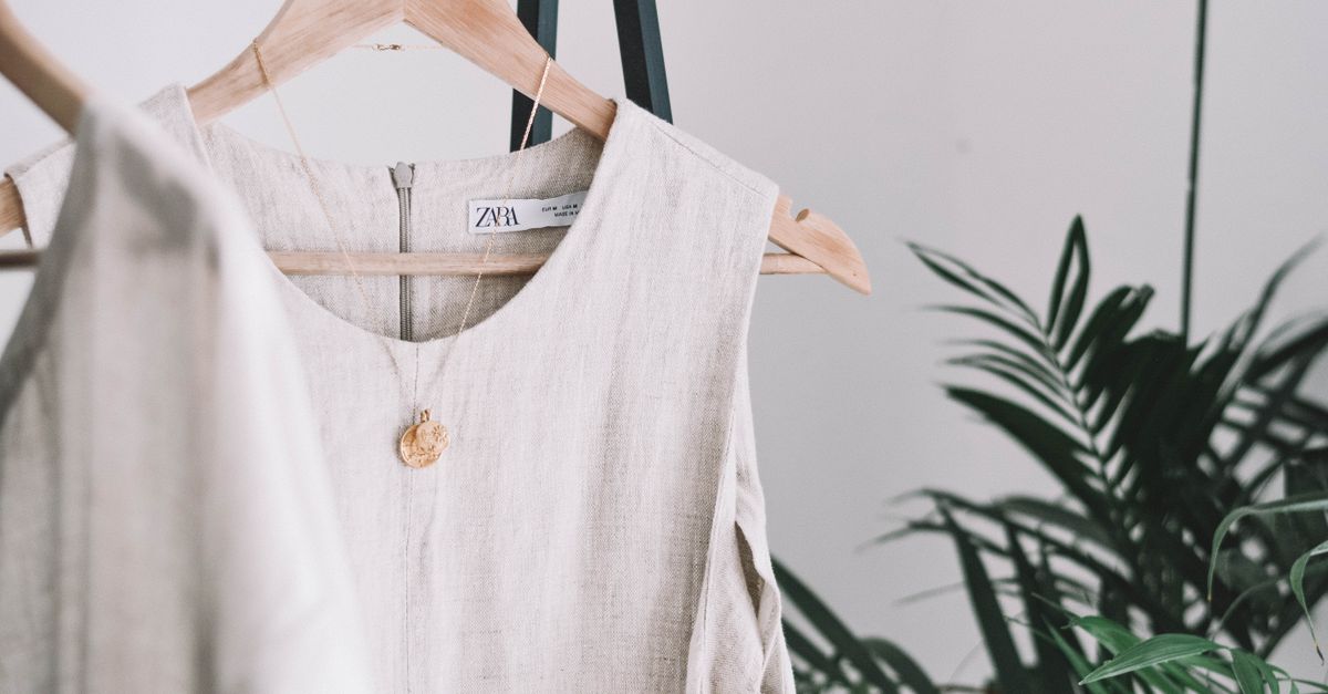 moda sostenible y estilo personal: Stylish beige dress hanging indoors, showcasing minimalist fashion amidst green plants.