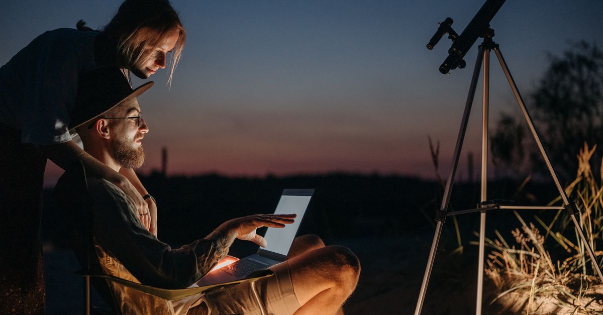 Calendario de eventos astronómicos de 2026 y consejos para observarlos con seguridad ciencia investigación: A couple using a laptop and telescope under the night sky, enjoying stargazing outdoors.