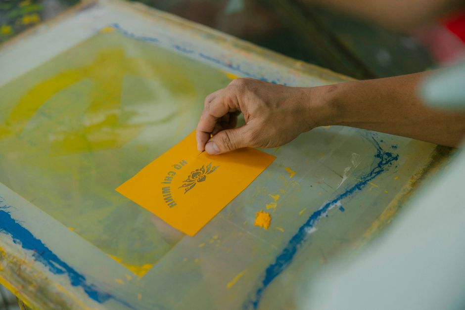 A detailed look at a hand screen printing, focusing on a yellow card with design.