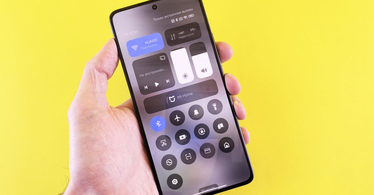 Cómo elegir un smartphone con IA en 2026 sin sacrificar privacidad ni control tecnología moderna: Close-up of a hand holding a smartphone against a vibrant yellow backdrop.