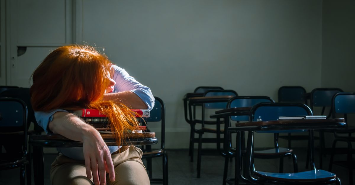 Sueño y recuperación: qué hábitos valen la pena y cuáles son solo moda bienestar practico educational neutral health: A tired student with red hair sleeps in an empty classroom under soft natural light.
