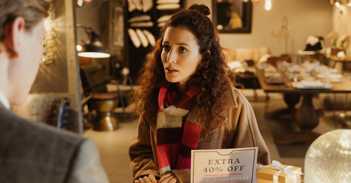 Cómo usar asistentes de IA para comparar compras sin ceder tus datos ni la decisión final tecnología moderna: Woman in a boutique store discussing with a salesperson during a sale.