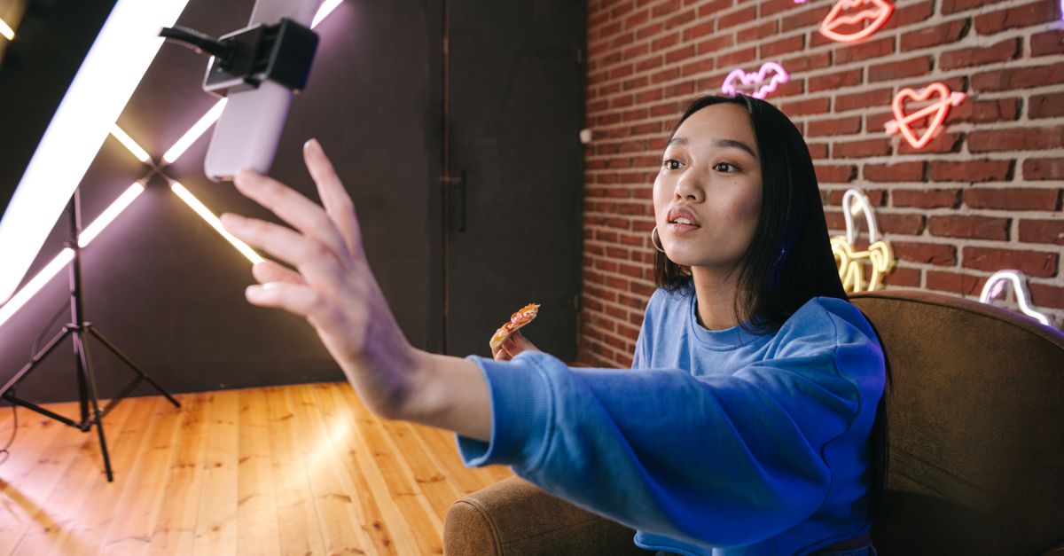 Búsqueda en TikTok, Instagram y YouTube: cómo encontrar información útil sin caer en desinformación social media technology: Asian woman creates live stream content in stylish neon lit room.