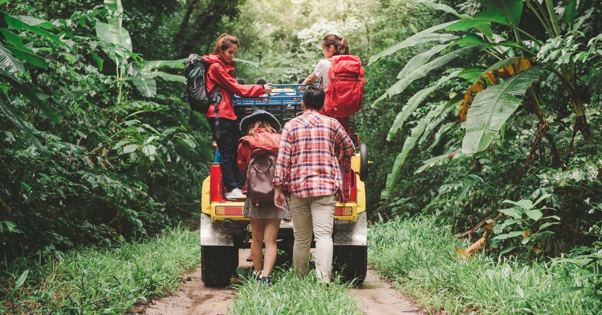 Viajes sostenibles gastar experiencias: Friends hiking in a tropical forest, riding a jeep with backpacks, enjoying the adventure.